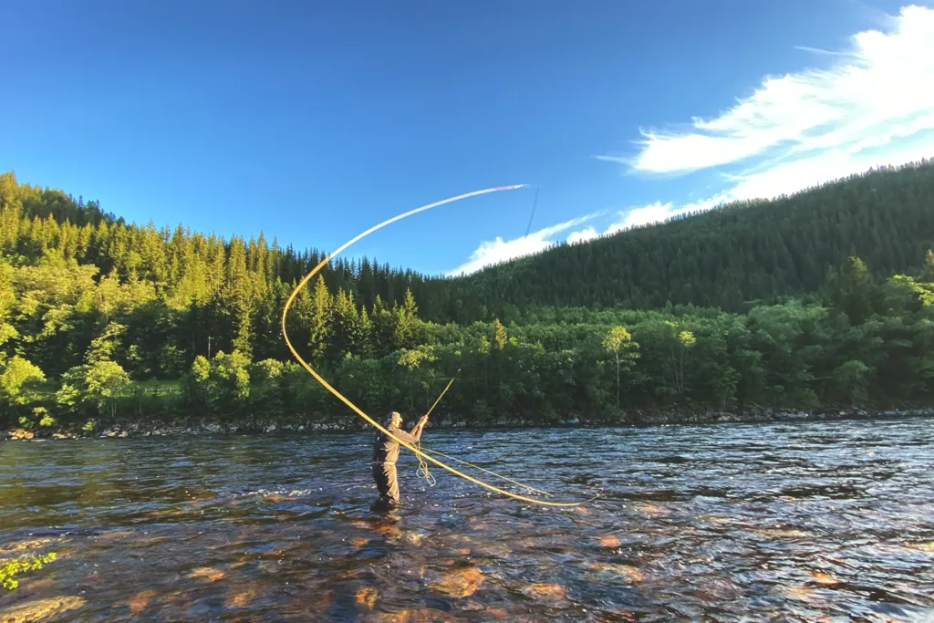 En mann fluefiske med Gaulaelva i bakgrunnen.