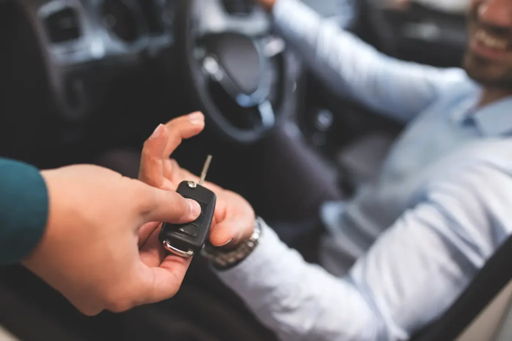 A man exchanging information by handing a car key to another man.