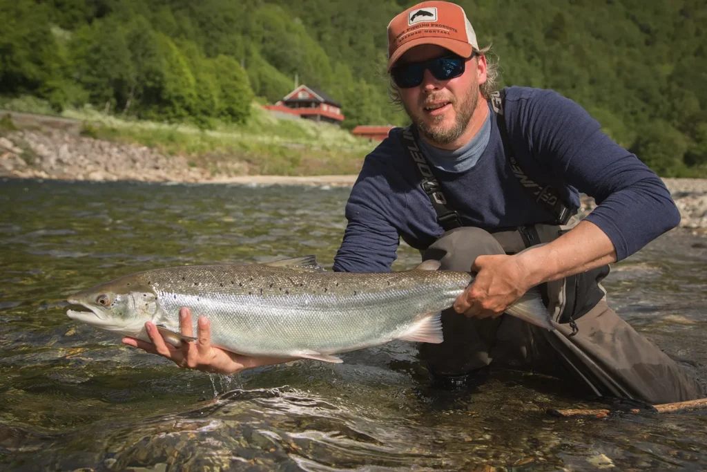 En mann som viser frem en fisk under Gaula-fiske.