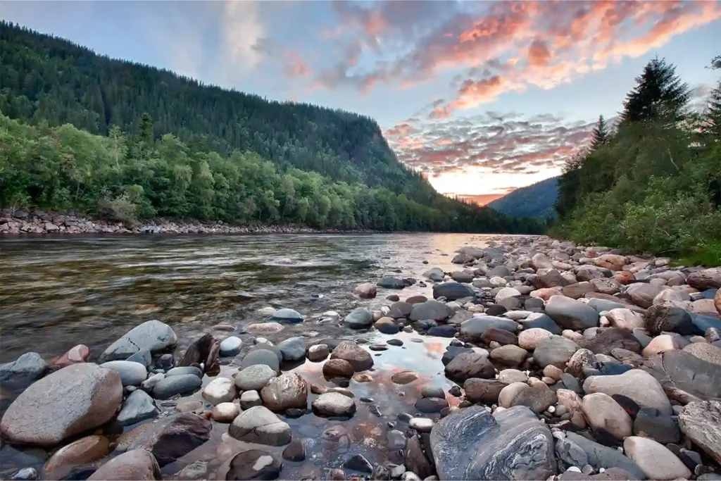 A river surrounded by rocks and trees at sunset.