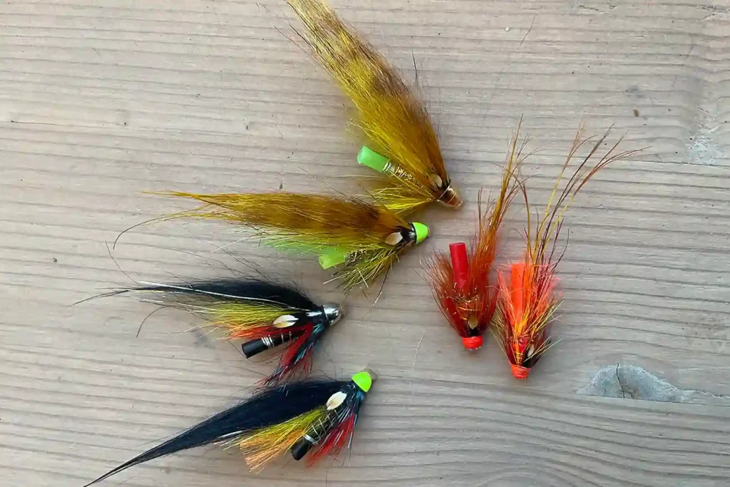 Four different types of fly flies on a wooden surface.